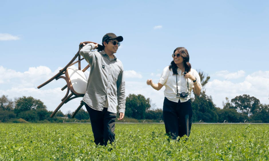 A happy couple walking in a lush green field on a sunny day, embracing nature.