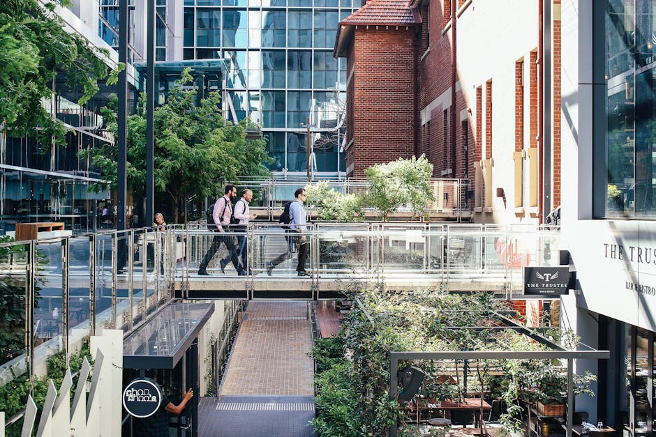 Office workers walking in a modern urban district with glass and brick buildings.