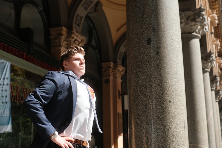 A determined man in a blue suit poses heroically outdoors under bright sunlight in Sydney, Australia.
